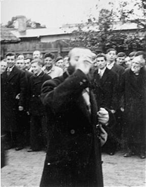 En religiøs jøde ydmyges offentligt, mens en folkemængde ser på. Polen, 1941 ©USHMM