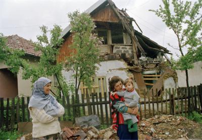 Bosniske muslimer foran ødelagt hus i byen Stari Vitez i Bosnien, 1994 © UN Photo by John Isaac
